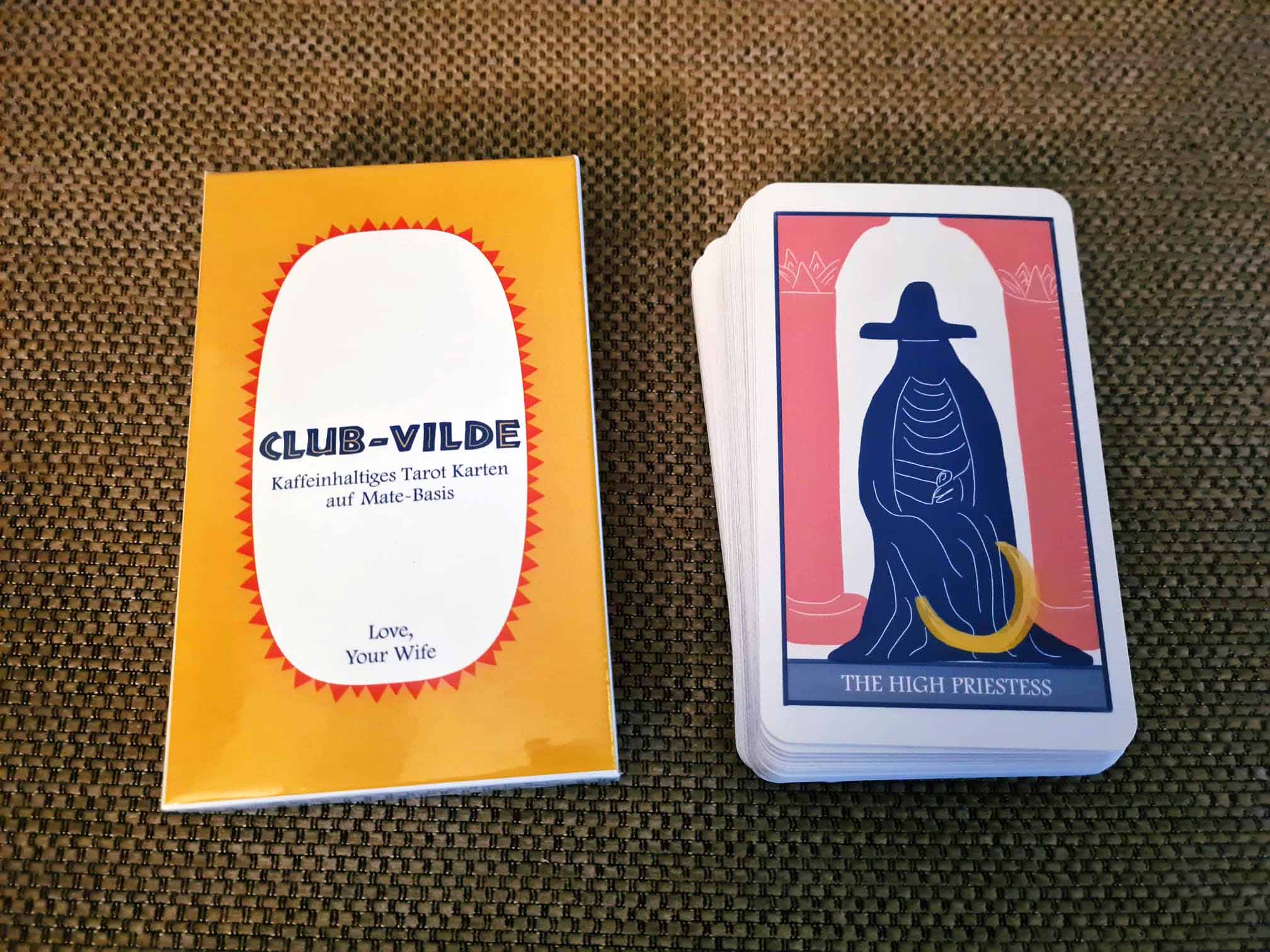 Stack of tarot cards and a yellow box on a cloth surface