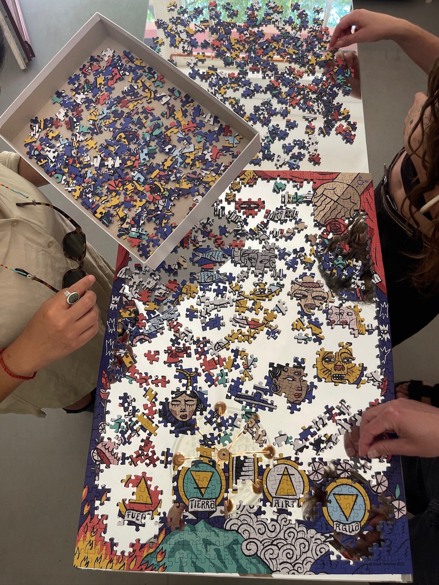 Two people working on a large puzzle with colorful pieces.