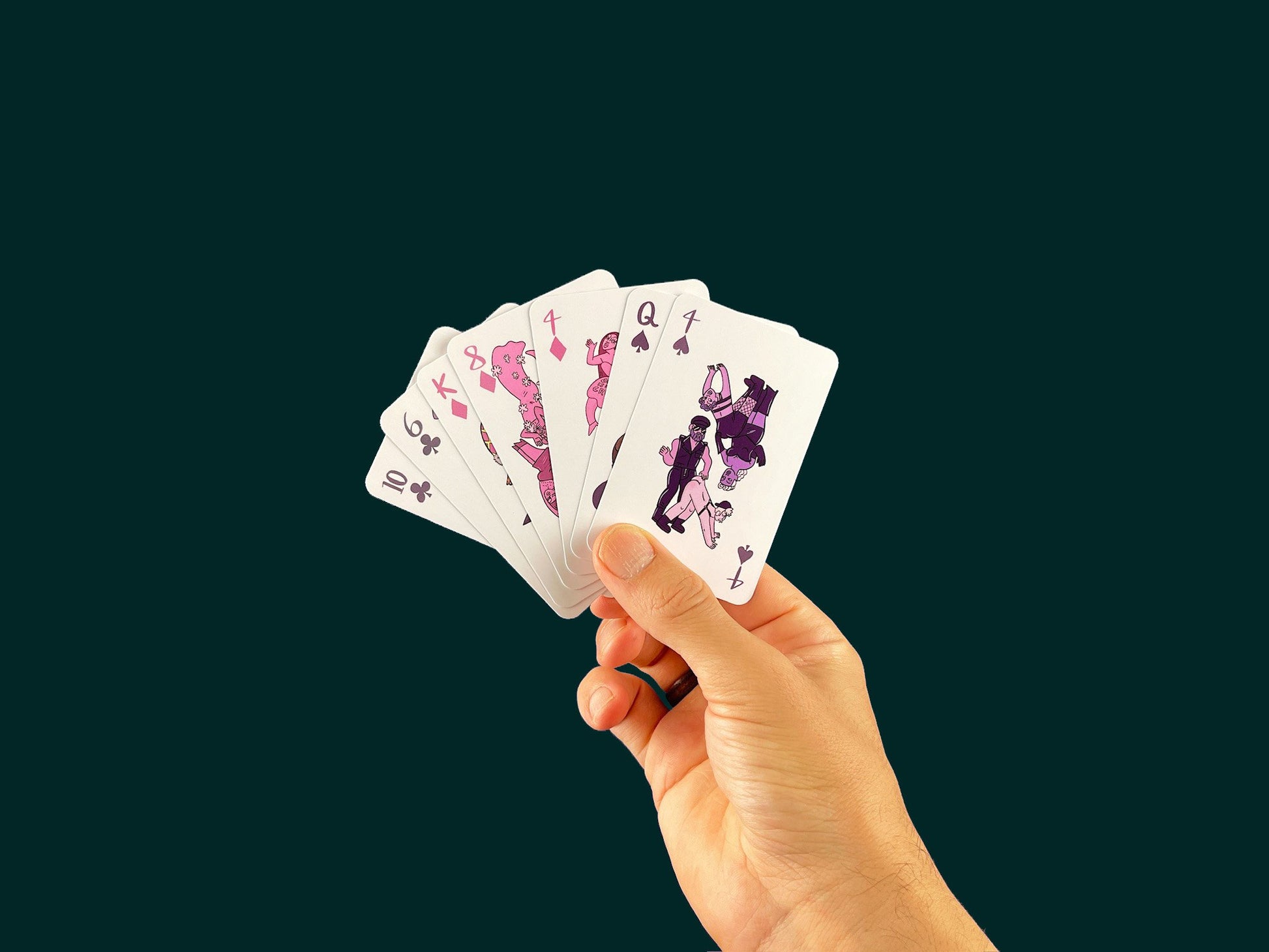 Hand holding Club of Queens playing cards, top card 4 of clubs with queer leather characters.