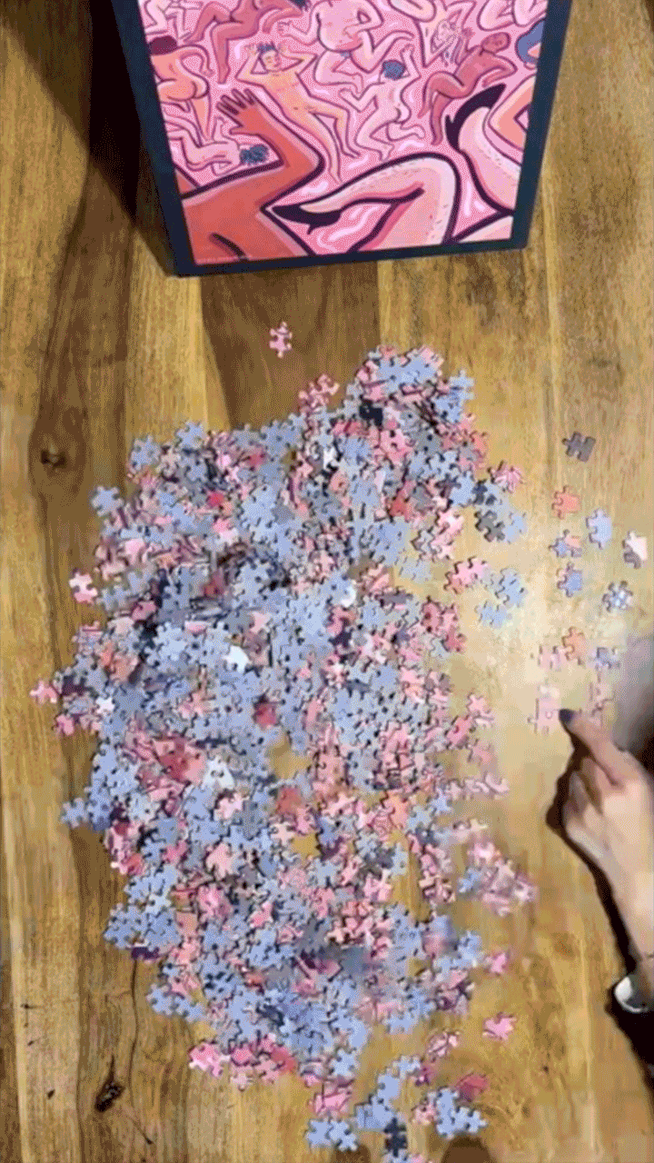 A stop-motion GIF of Rory Midhani's LGBTQIAUFO puzzle in stages of completion. At one point a head wearing a bright orange hat comes in the foreground.