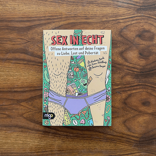 The book "Sex in Echt" on a dark wood table. The cover shows fun and playful cartoons around two legs.