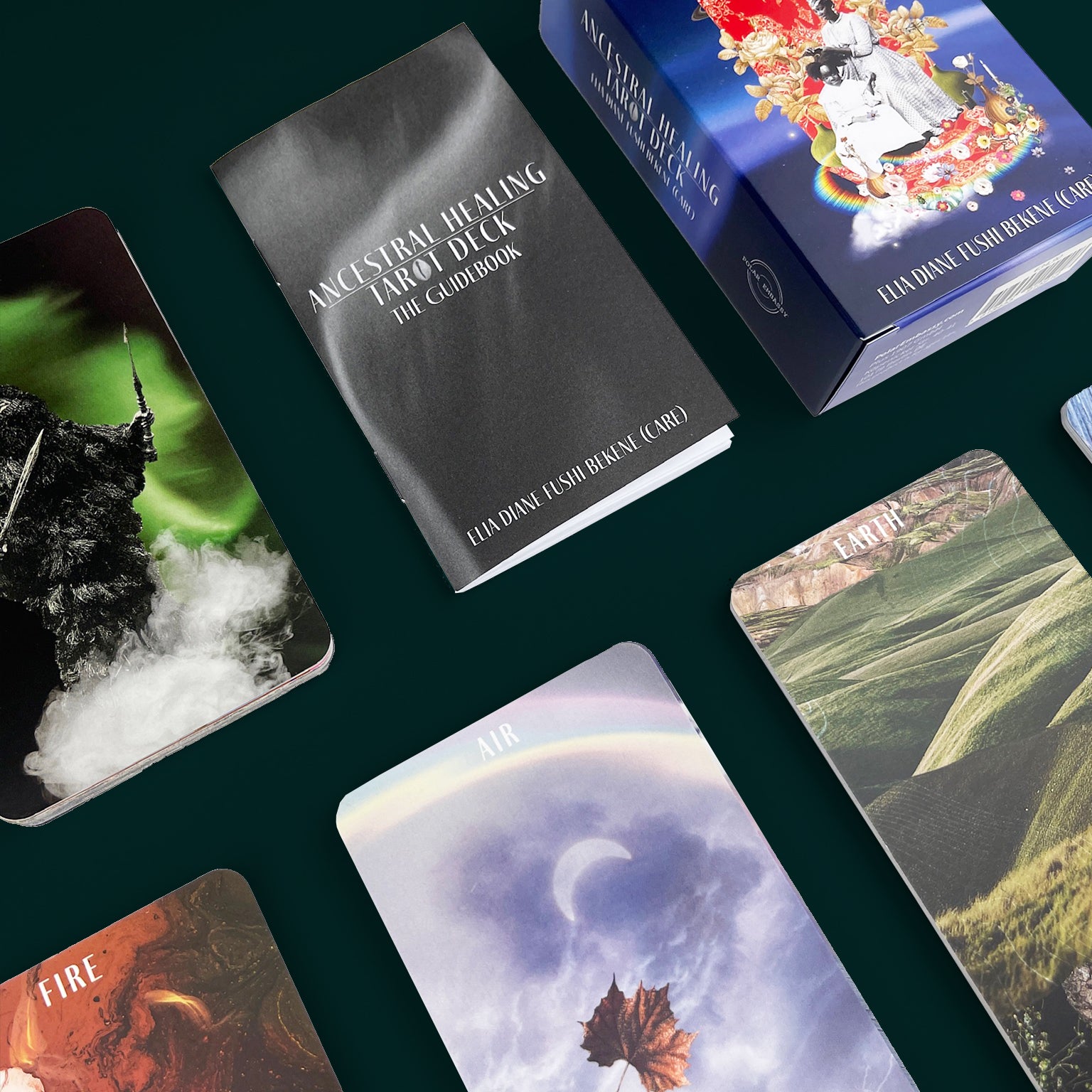 A deck of Tarot cards is laid on a dark green background. The box is bright blue, with the title "Ancestral Healing Tarot Deck", with a guiebook, and five stacks of cards visible. 