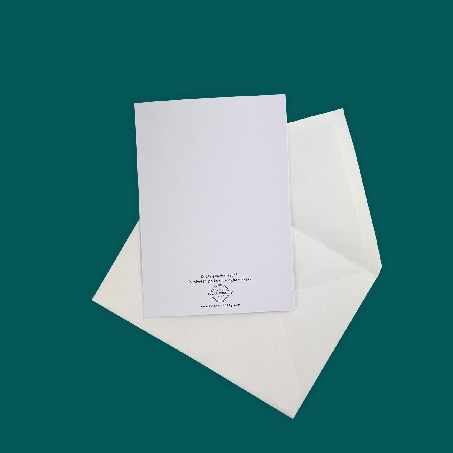 The back of a white greeting card and a white envelope. On the bottom of the card is the text "© Rory Midhani 2024, Printed in Berlin on recycled paper" and the Polar Embassy logo, with three black lines, and "www.polarembassy.com". Against a glacial green background.