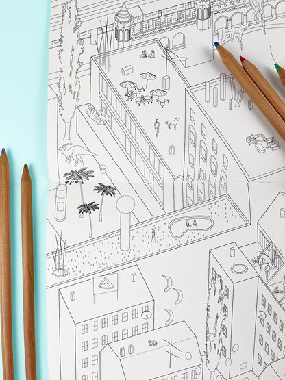 Photo of coloring book on a light blue background with colored pencils. The scene in the book is Kreuzberg with dinosaurs and whimsical elements.