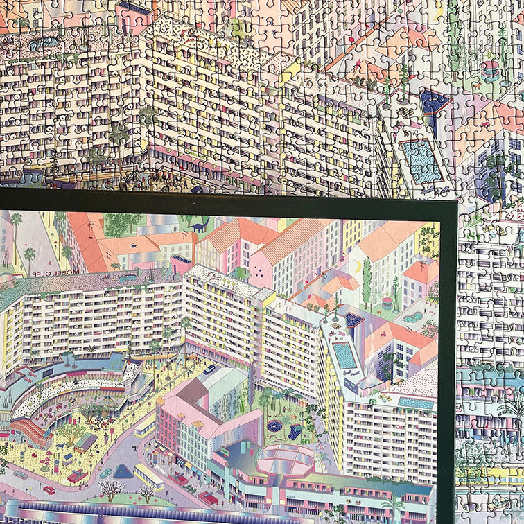 A puzzle box showing a colorful illustration of Kottbusser Tor "Kotti" in Berlin Kreuzberg with dinosaurs. Behind the box is the completed puzzle.