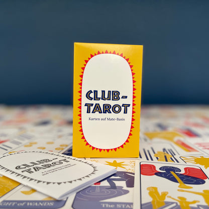 A colorful boxed deck of Tarot cards sits on the cards laid out, with the guidebook nearby. Against a dark blue background.