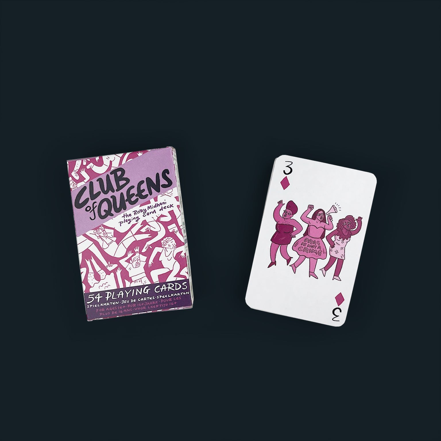 A pink and purple box of playing cards next to a stack of cards with the three of diamonds on top. On the card are three drag queens, the middle wearing a dress that says "Drag is not a crime".