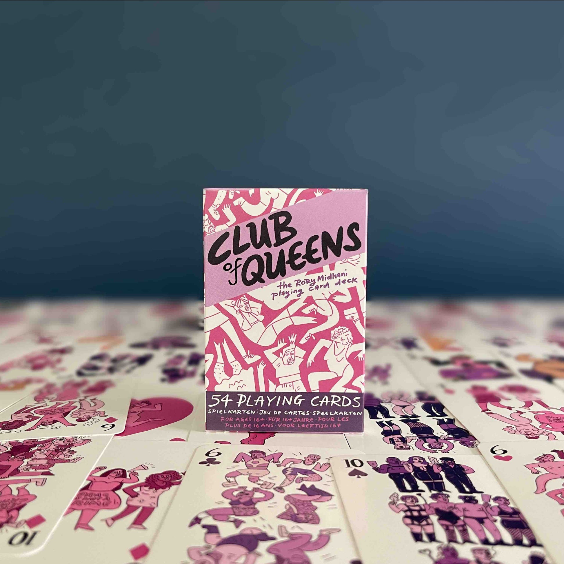 Pink and purple box of playing cards on top of the cards, in front of a dark blue background.