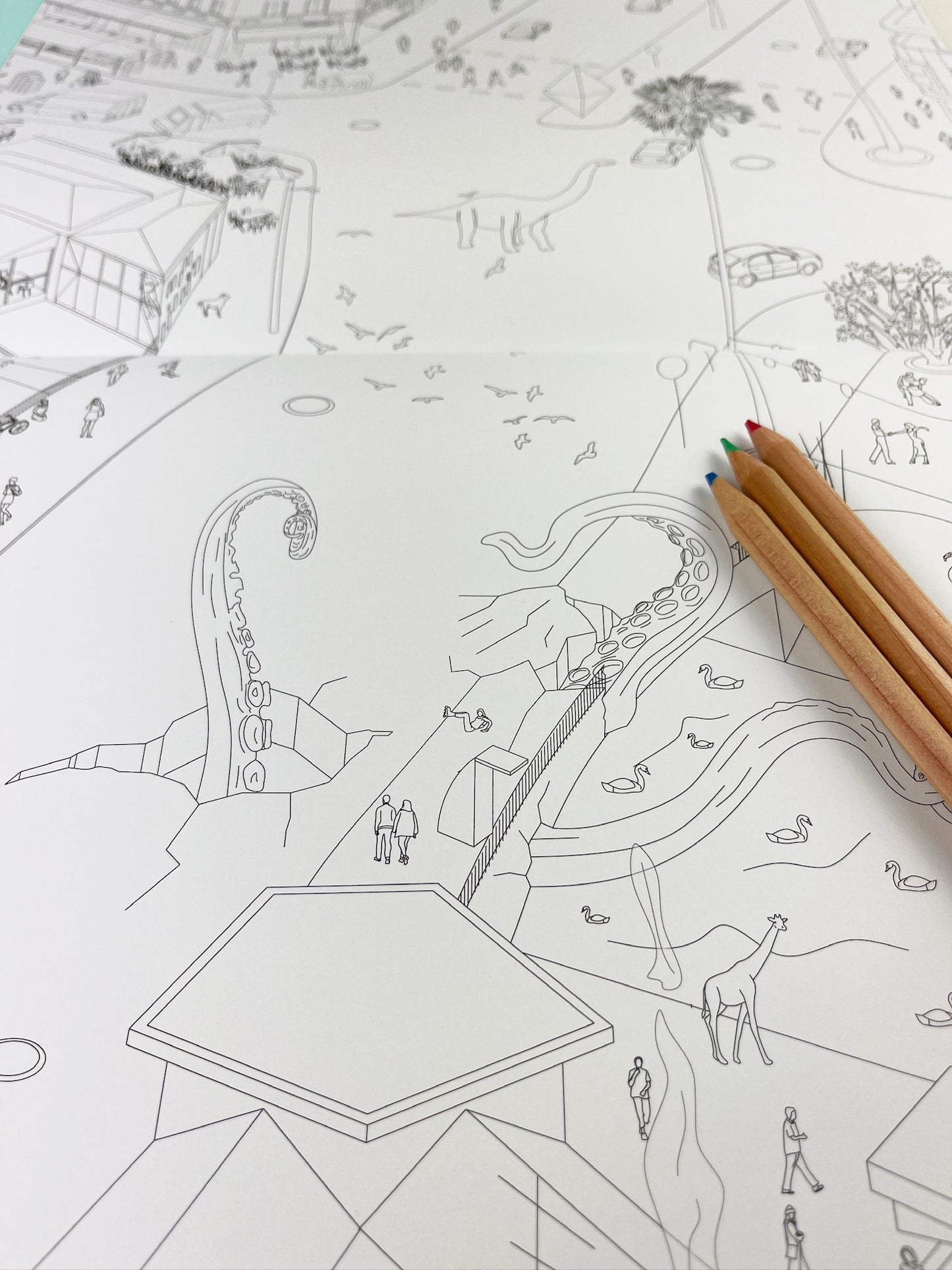 An open page of the coloring book Isomatic Berlin from Polar Embassy. On the page is a giant octopus breaking through Kottbusser Brücke in Berlin Kreuzberg. Three colored pencils lay on the page.