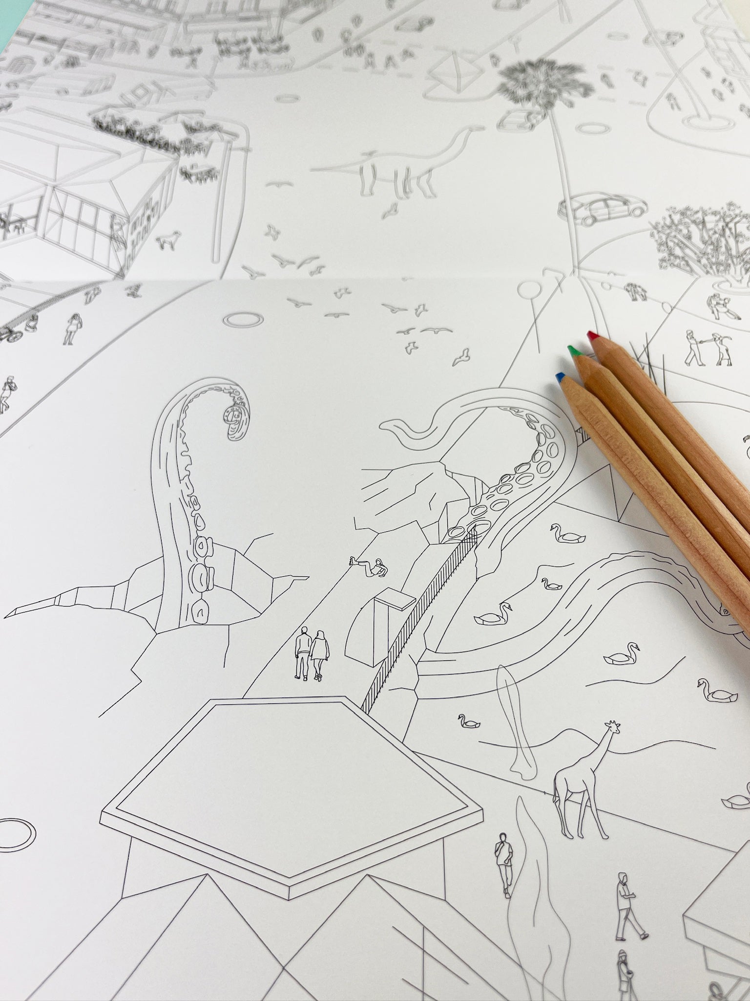 An open page of the coloring book Isomatic Berlin from Polar Embassy. On the page is a giant octopus breaking through Kottbusser Brücke in Berlin Kreuzberg. Three colored pencils lay on the page.