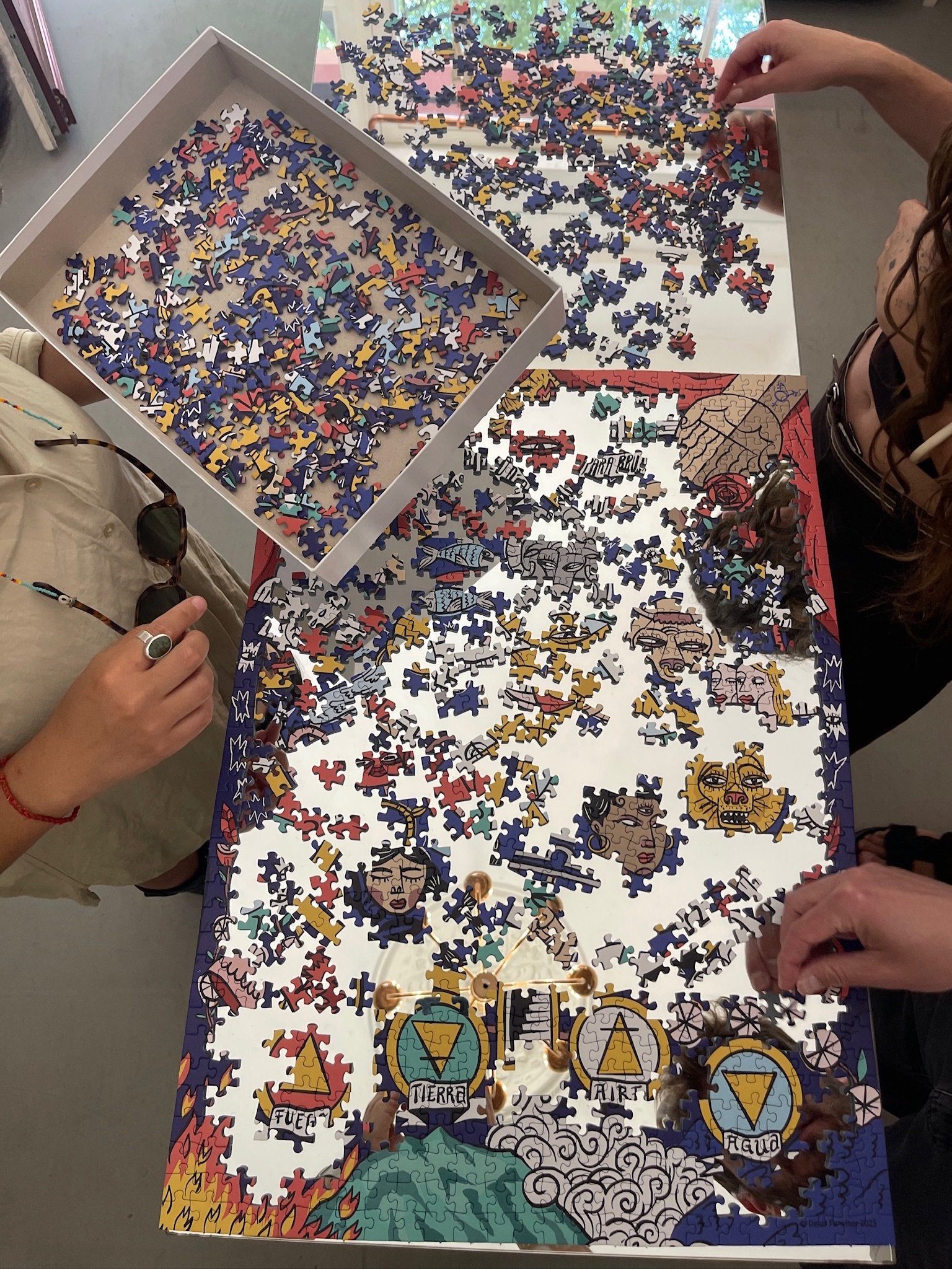 Two people assembling colorful astrology zodiac jigsaw puzzle on table.
