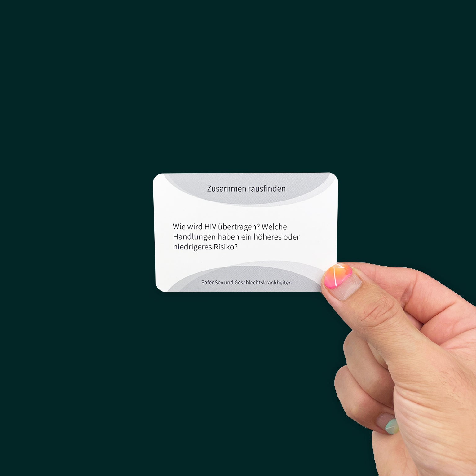 A card with bright pink and orange nail polish holds a card that reads "Zusammen rausfinden:
Wie wird HIV übertragen? Welche Handlungen haben ein höheres oder niedrigeres Risiko? Safer Sex und Geschlechtskrankheiten"