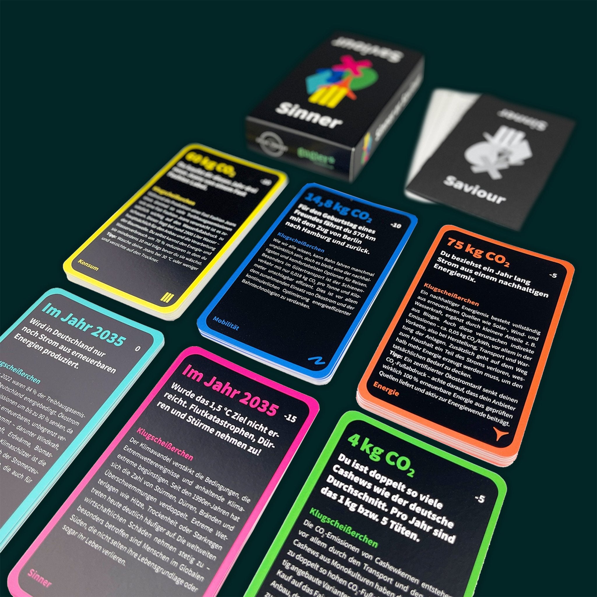 Spielkarten des Klimaschutz Kartenspiels Sinner or Saviour (Mobilität, Energie Kategorien) auf dunkelgrünem Hintergrund.