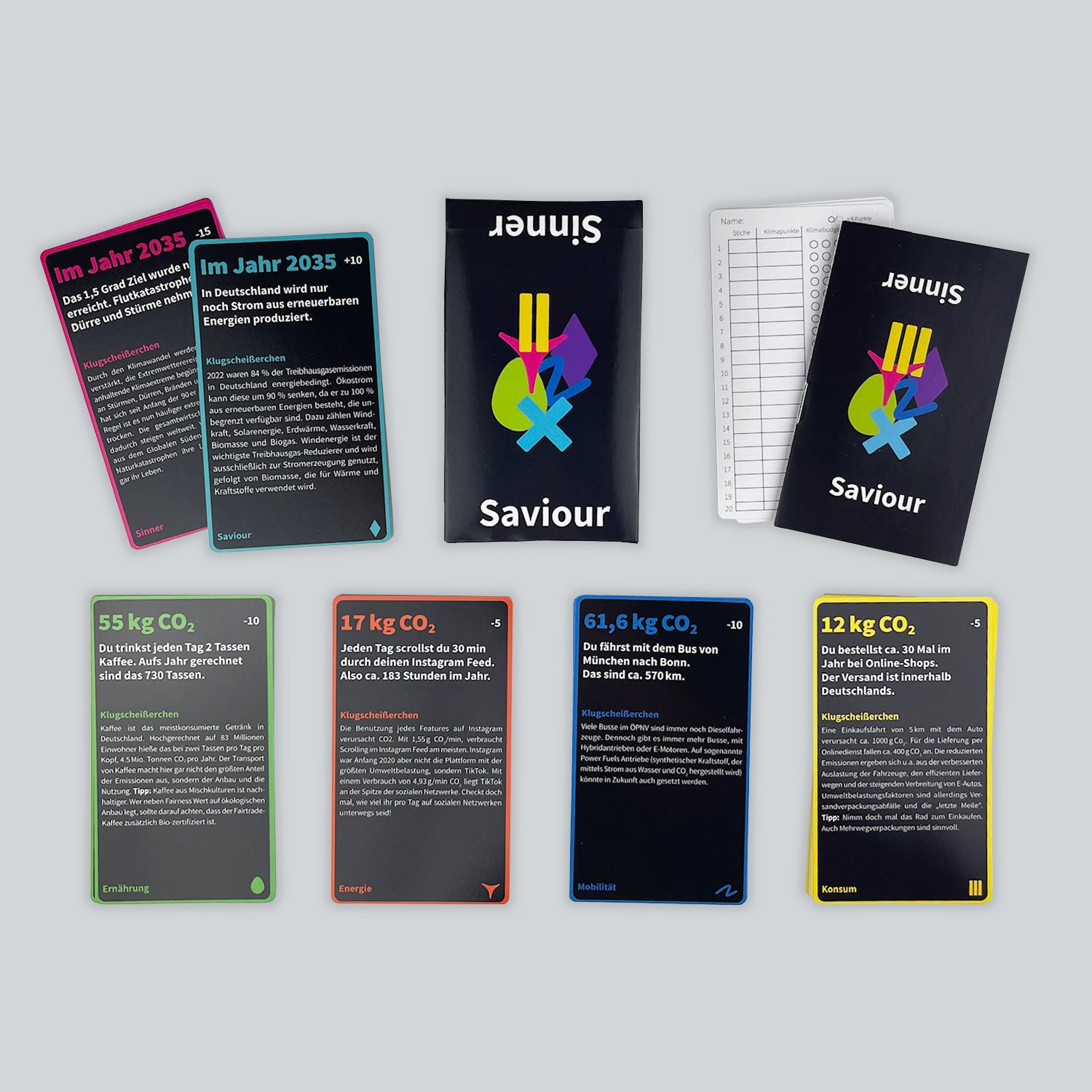 A view of the educational game Sinner or Saviour from above. Cards are stacked in 6 categories (Mobility, Energy, etc.), with the box, scorecards, and guidebook against a light gray background.