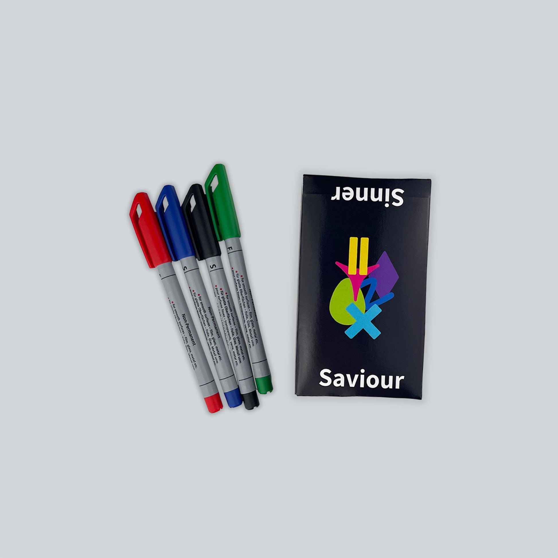 A boxed set of the educational game Sinner or Saviour sits on a light gray background, along with four dry erase markers used for the scorecards.