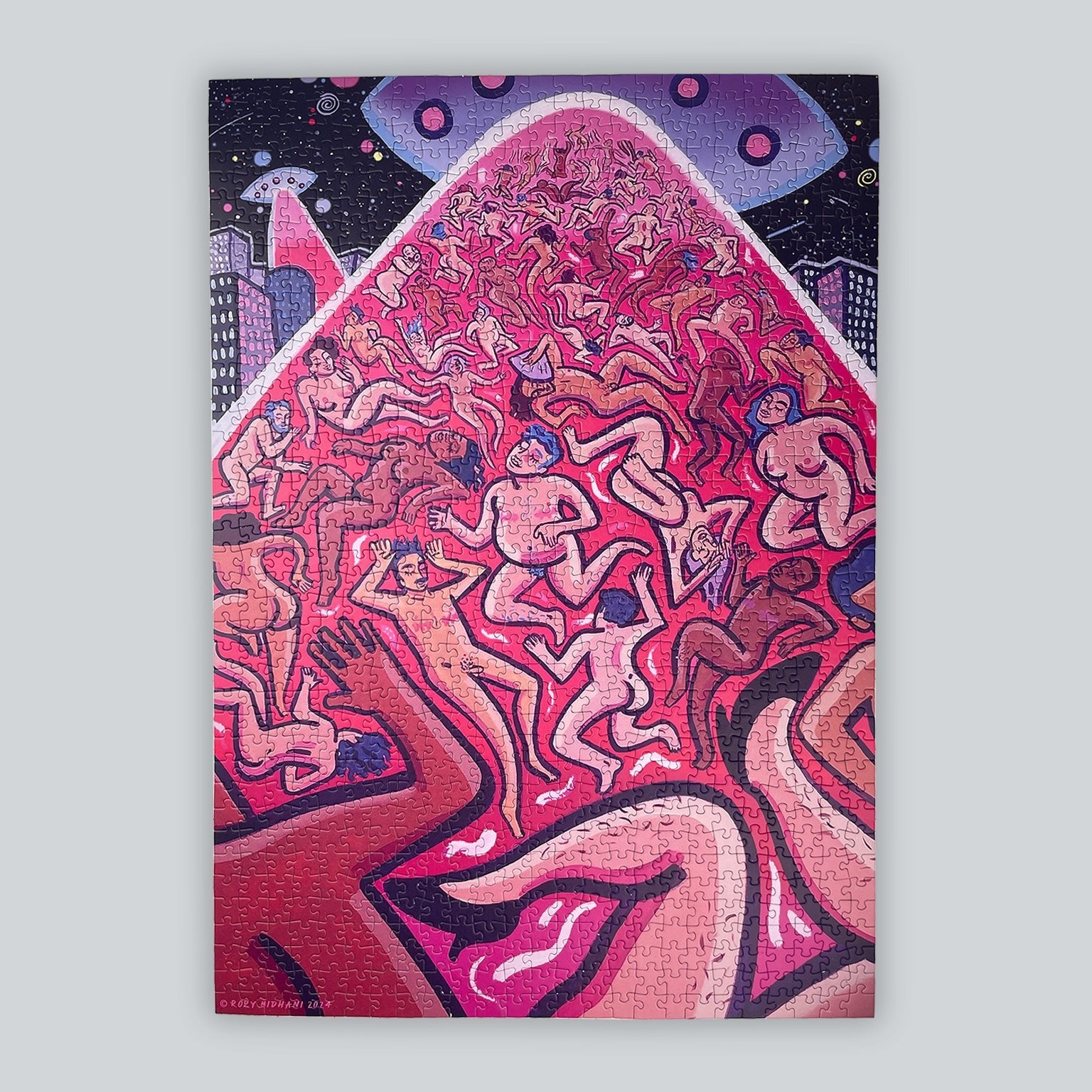 A completed rectangular art puzzle featuring a stylized, colorful illustration of many nude trans* and queer human figures being light-beamed up by a flying saucer in a dark starry sky above, shown against a light gray background.