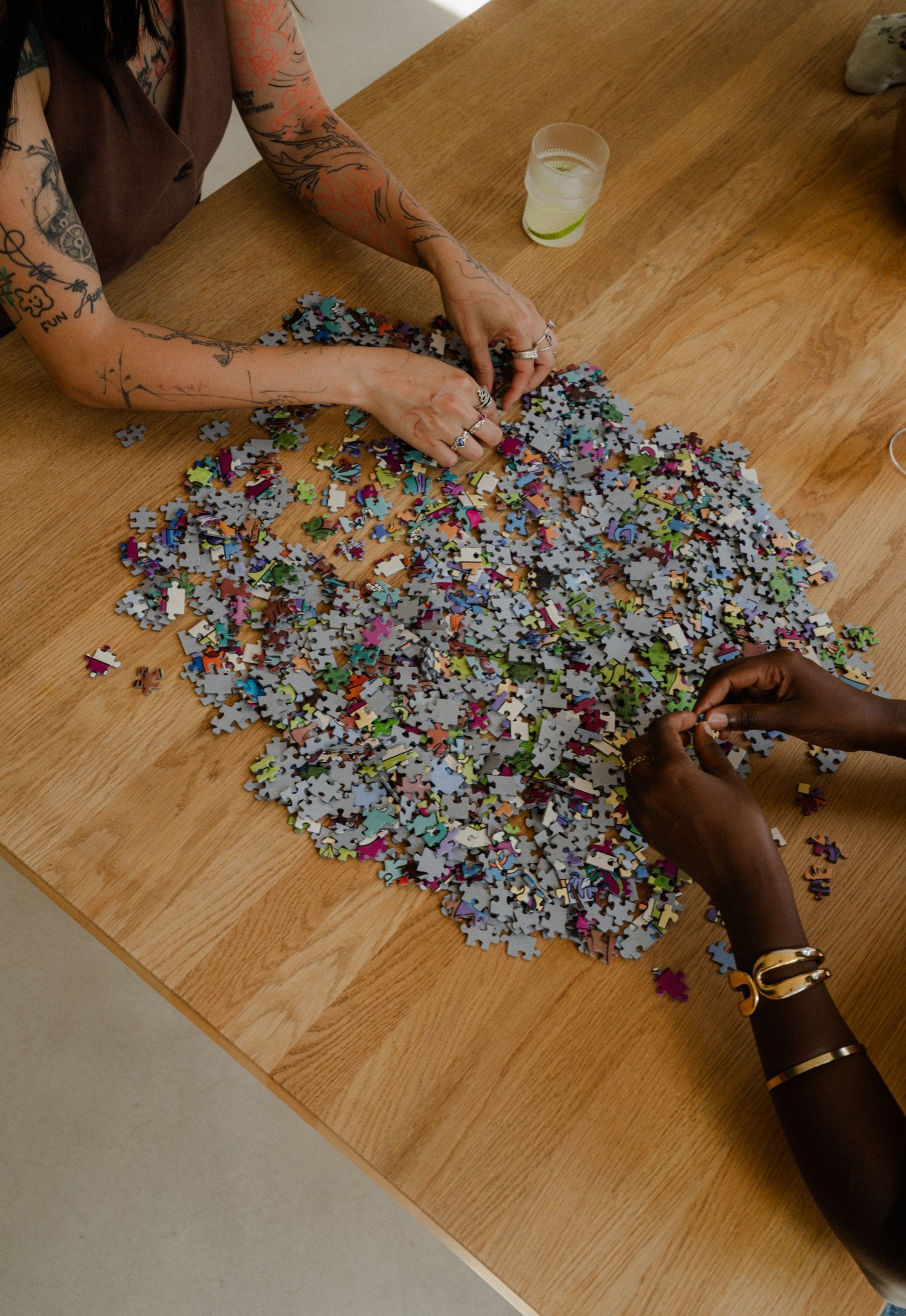 Hands sorting loose pieces of the Be Crime, Do Queer 1000-piece queer puzzle by Louie Läuger.