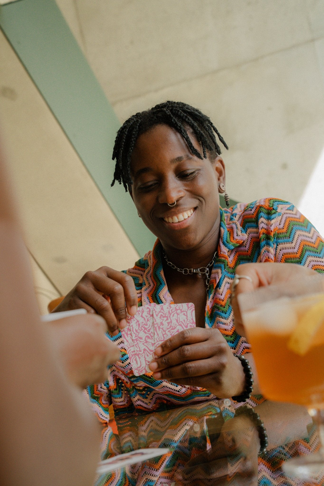 Person laughing over a game-night hand of Club of Queens queer playing cards by Rory Midhani.