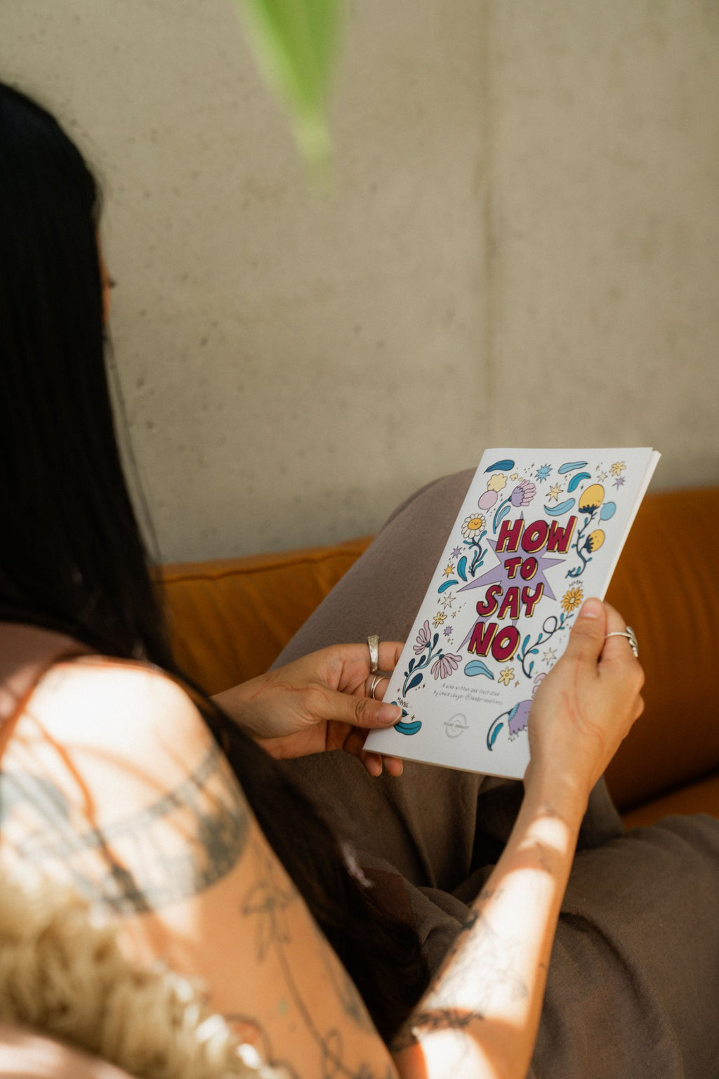 Hands holding the How to Say No workbook on consent and boundaries, illustrated by Louie Läuger.