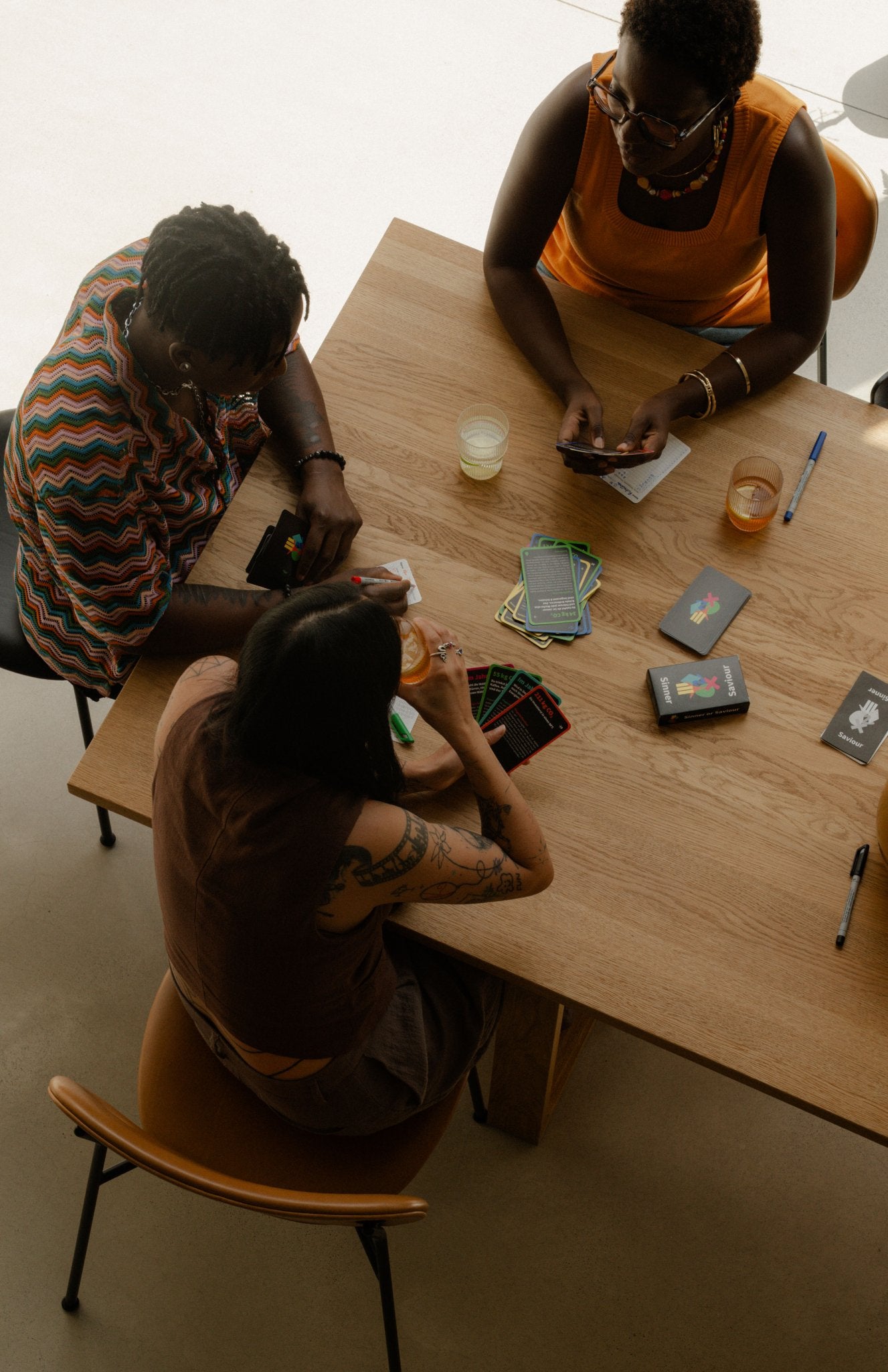 Drei Personen spielen Sinner or Saviour, das Klimabildungs-Kartenspiel von Polar Embassy, am Tisch.