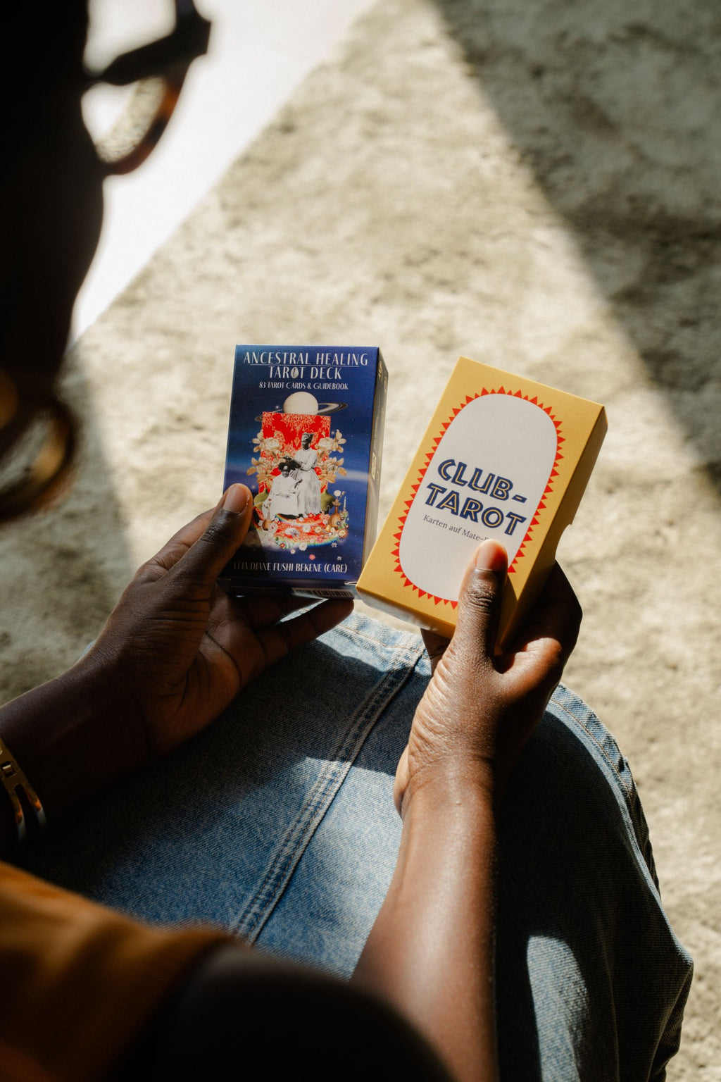Hands holding Polar Embassy's two tarot decks: Ancestral Healing Tarot and beginner Club Tarot.