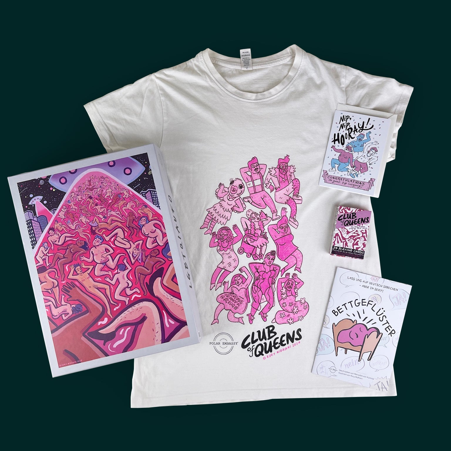 A white cotton t-shirt with pink drag queens, a deck of playing cards, a workbook, and a puzzle by Rory Midhani against a dark green background